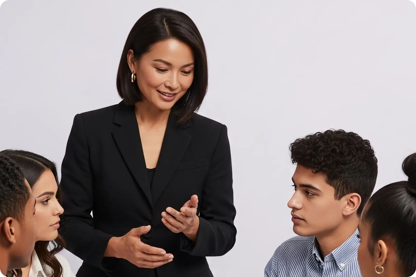 Woman in black blazer speaking to three attentive individuals in a group discussion setting.
