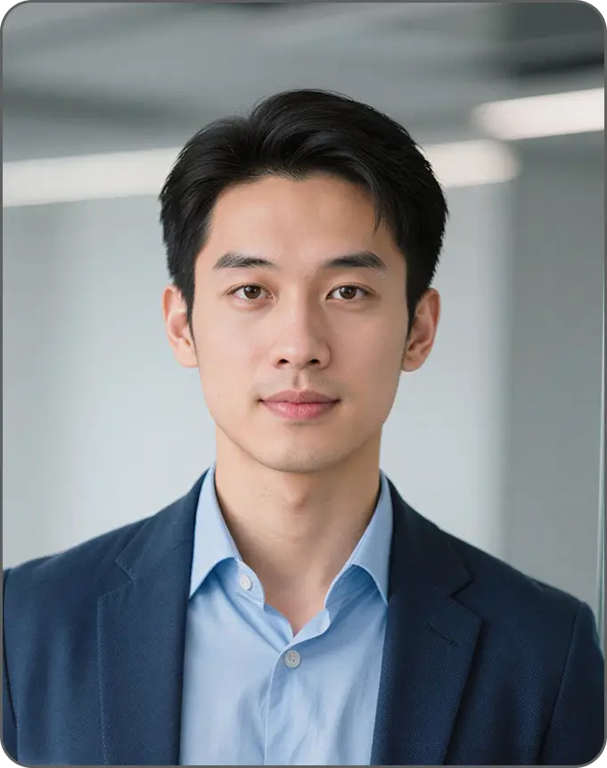 Portrait of a young Asian man wearing a blue dress shirt and dark blazer in an office setting.
